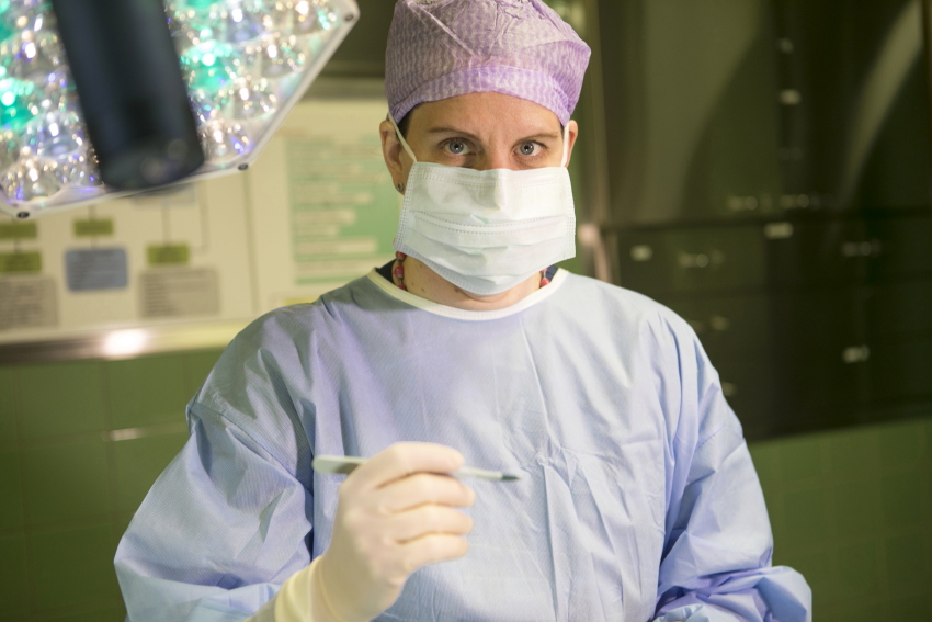 Kuvassa kirurgina toimiva Kati Kortelainen kuvattuna leikkaussalissa. Kortelainen katsoo kameraan.