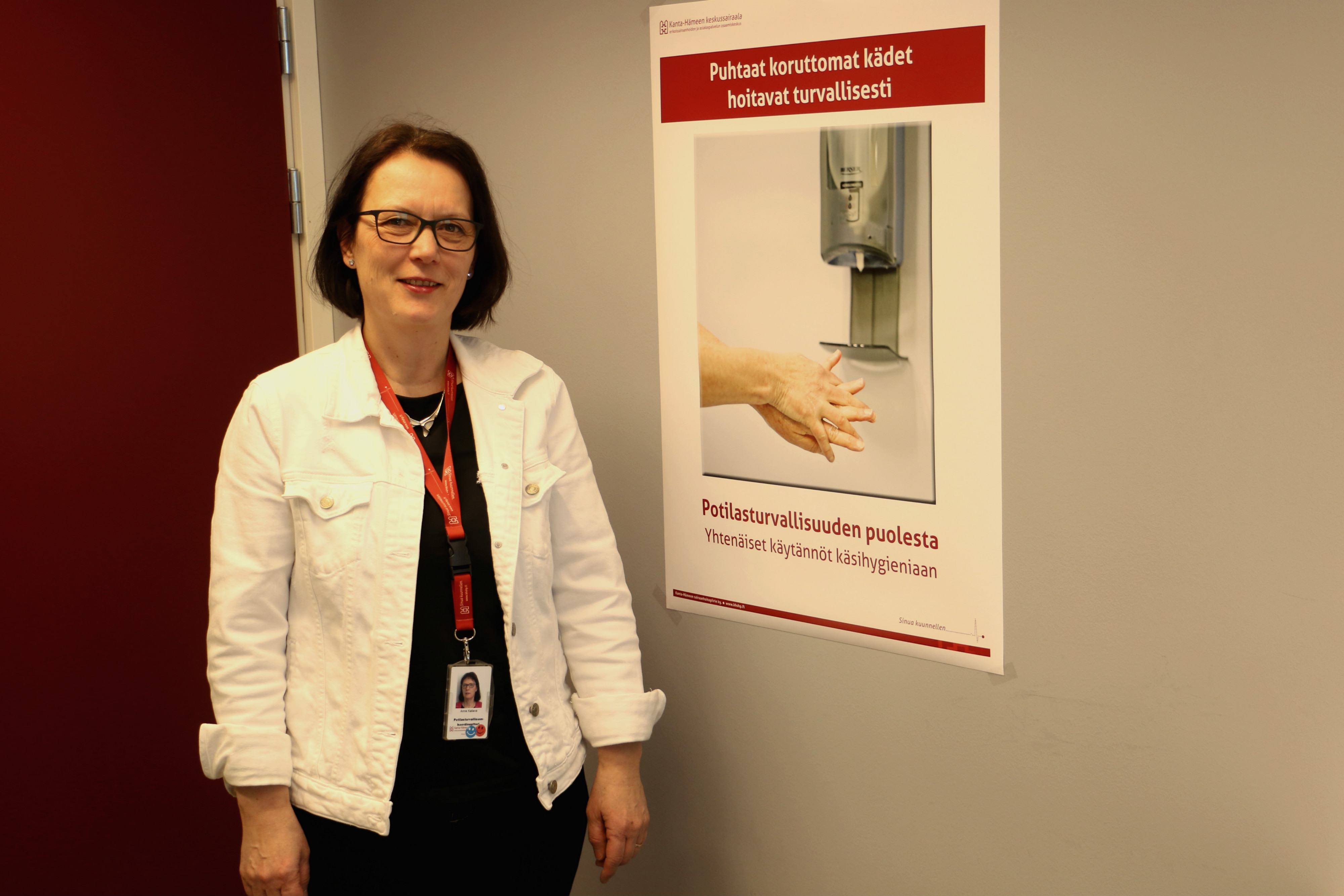 Anne Kallava Kanta-Hämeen keskussairaalassa käsihygieniasta tiedottavan julisteen edessä.